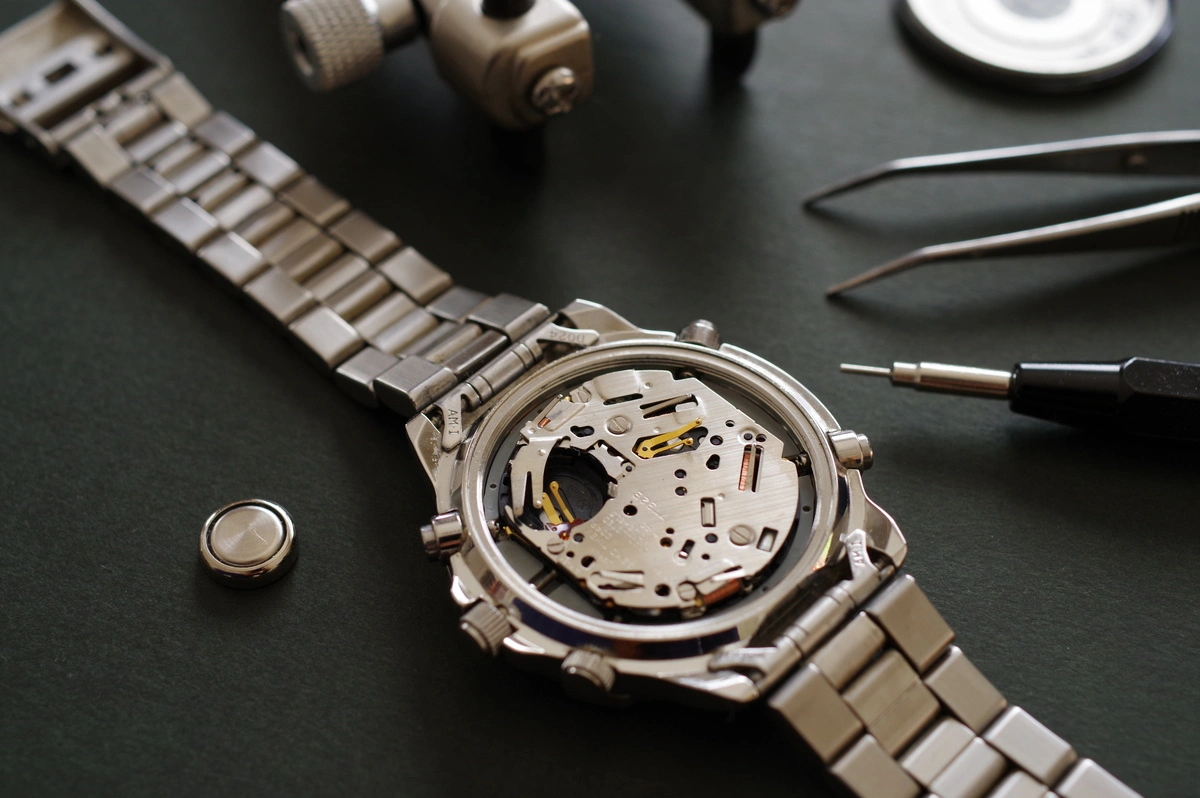 Montre mécanique ouverte avec des outils de réparation de précision, illustrant un réparateur de montres en pleine intervention technique.